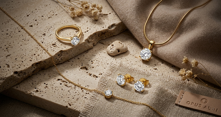 OPUS💎AURI "Götterfunken" Set: Ring, Kette, Ohrringe & Armband in 18K Gelbgold-PVD mit Labordiamanten. Wabi-Sabi Design auf Travertin & Leinen. Repräsentiert Silent Luxury & Eleganz aus Schaffhausen. Handverlesener Schmuck für festliche Momente.